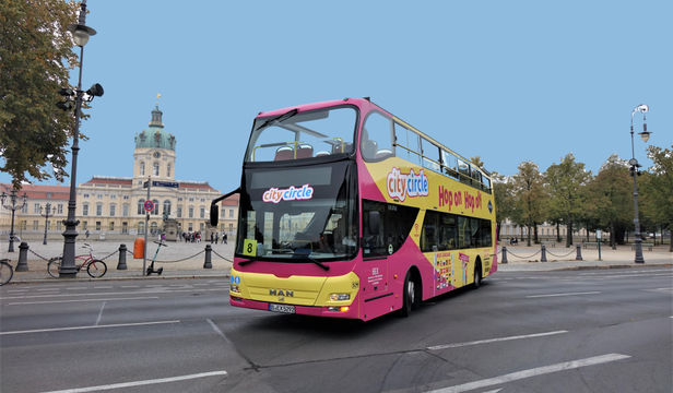A vibrant Hop-on Hop-off bus navigates through the streets of Berlin, offering tours of the city's famous landmarks.