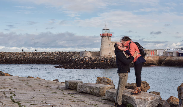 A blissful couple relishing the serene coastal beauty of Dublin, creating precious memories by the shimmering shores.