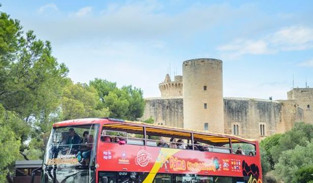 Dynamic red City Sightseeing Hop-on Hop-off bus touring Mallorca, offering passengers stunning sights and panoramic views of the island.