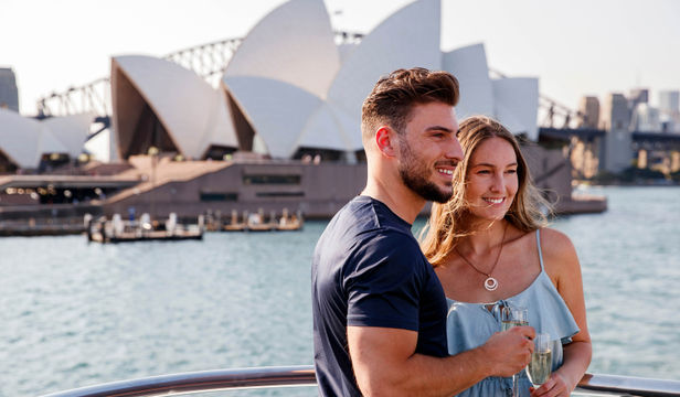 Adorable couple strikes a pose on the cruise ship's deck, framed by the iconic harbor cruise, capturing love against beauty.
