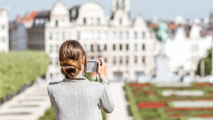 A young traveler holding a camera as she admires and records the magnificent architecture and beauty of Brussels.
