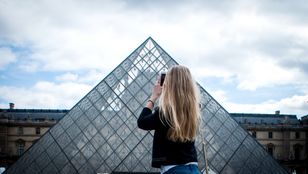 Discover the beauty of the Louvre Museum through the lens of a young girl, capturing its elegance with her camera in hand.