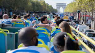 Excited tourists savoring an open tour bus ride in Paris, en route to the iconic Arc de Triomphe, relishing every moment of their journey.