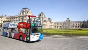 Toot bus Paris with majestic backdrop of Grand Louvre Museum: A captivating blend of modern transportation and cultural heritage.