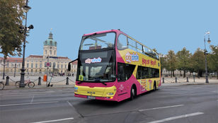 A vibrant Hop-on Hop-off bus navigates through the streets of Berlin, offering tours of the city's famous landmarks.