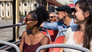 Excited tourists savoring their Big Bus Berlin ride, delighting in the city's sights and attractions from the hop-on hop-off bus.