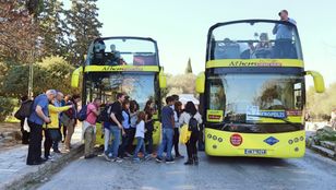 Two vibrant yellow buses eagerly awaiting passengers, ready for exciting city exploration, as enthusiastic passengers embark on their adventure.
