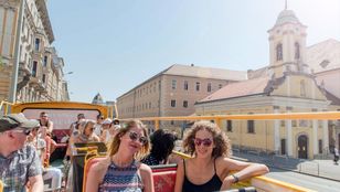 Joyful passengers immersed in the mesmerizing beauty of Budapest while sitting in a bright red hop-on, hop-off bus.