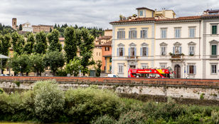 Vibrant streets of Florence come alive with the bright red City Sightseeing Florence Hop-On, Hop-Off bus, radiating beautiful vibes all around.