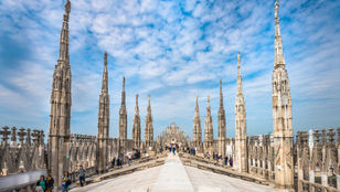 Top view of Milan's Duomo Cathedral, tourists immersed in admiration, exploring and marveling at its breathtaking exterior beauty.