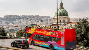 Energetic sightseeing bus traverses Naples, Italy, with a full load of passengers experiencing the city's attractions.
