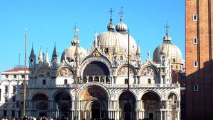 St. Mark's Basilica, a magnificent sight from afar, with tourists admiring its grandeur and beauty from the outside.