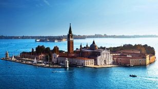 Aerial shot captures Venice's cityscape amidst the sea, providing a stunning view of its distinctive layout and architectural marvels.