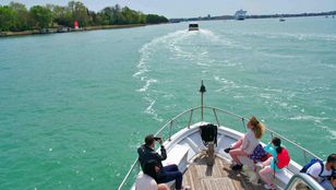 A cruise ship moves through Venetian waters, providing tourists with stunning views and immersive island experiences.
