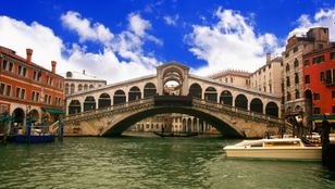 A stunning photo captures the beauty of Venice's canals and Rialto Bridge, epitomizing the city's historic charm and allure.
