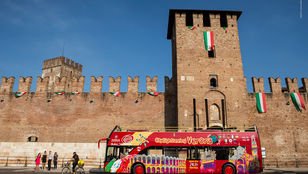 A vibrant red Verona Hop-on Hop-off bus patiently awaits passengers, ready to embark on a delightful city exploration.