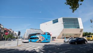 Bright blue Gray Line Porto Hop-On Hop-Off Bus gracefully cruising through the vibrant streets of Porto, ready to showcase the city's charm.