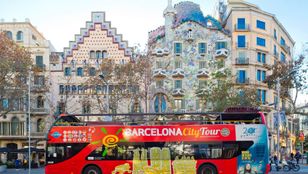 Vibrant red Hop-on Hop-off bus framed by Barcelona's iconic Gaudi architecture, a striking fusion of colors and culture.