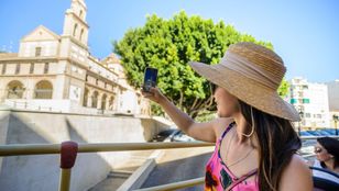 Young traveler capturing the beauty of Carmen Thyssen Museum in Malaga from a comfortable seat on the Hop-On Hop-Off bus.