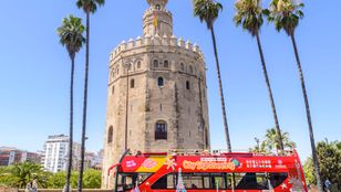 Bright red City Sightseeing Seville Hop-On, Hop-Off open tour bus with passengers exploring the vibrant streets of Seville.