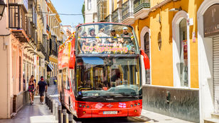 Vibrant Seville hop-on hop-off bus ride with tourists immersed in lively atmosphere, savoring the surroundings and joyful journey.