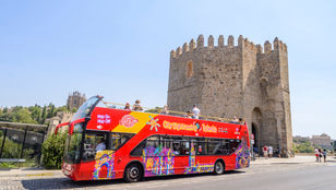 Toledo's bright red hop-on hop-off bus in motion, with passengers relishing the scenic journey on a bustling and lively bus.