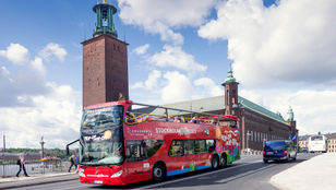 Red Sightseeing Stockholm Hop-On, Hop-Off Bus gracefully glides through the streets, offering a captivating tour of Stockholm.