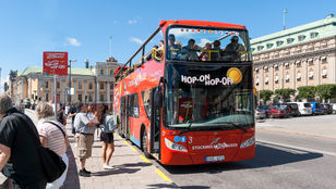 Passengers eagerly await to hop on the Red Sightseeing Stockholm, their expressions filled with anticipation for the open tour bus adventure.