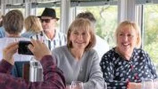 Tourists revel in drinks and photo ops aboard the Q Train, Melbourne, creating unforgettable memories and capturing the moments.