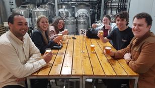 Friends gathered around a table, sharing laughter and beers, their joyful smiles freeze in a photo, capturing unforgettable moments.