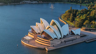 Stunning aerial shot showcases Sydney Opera House's iconic architecture amidst breathtaking cityscape and shimmering waters.