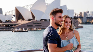 Adorable couple strikes a pose on the cruise ship's deck, framed by the iconic harbor cruise, capturing love against beauty.